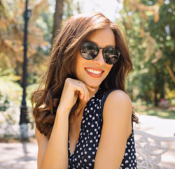 beautiful brunette sitting outside smiling wearing sunglasses